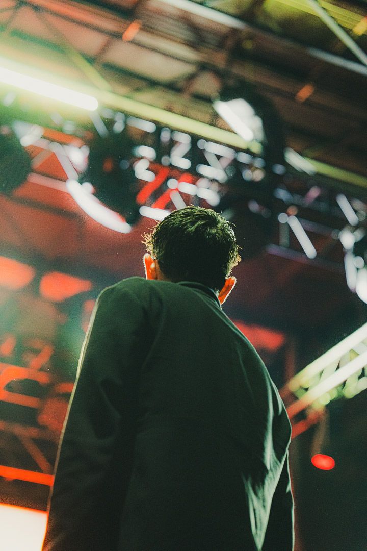 Performer silhouetted against colorful stage lighting during live show.