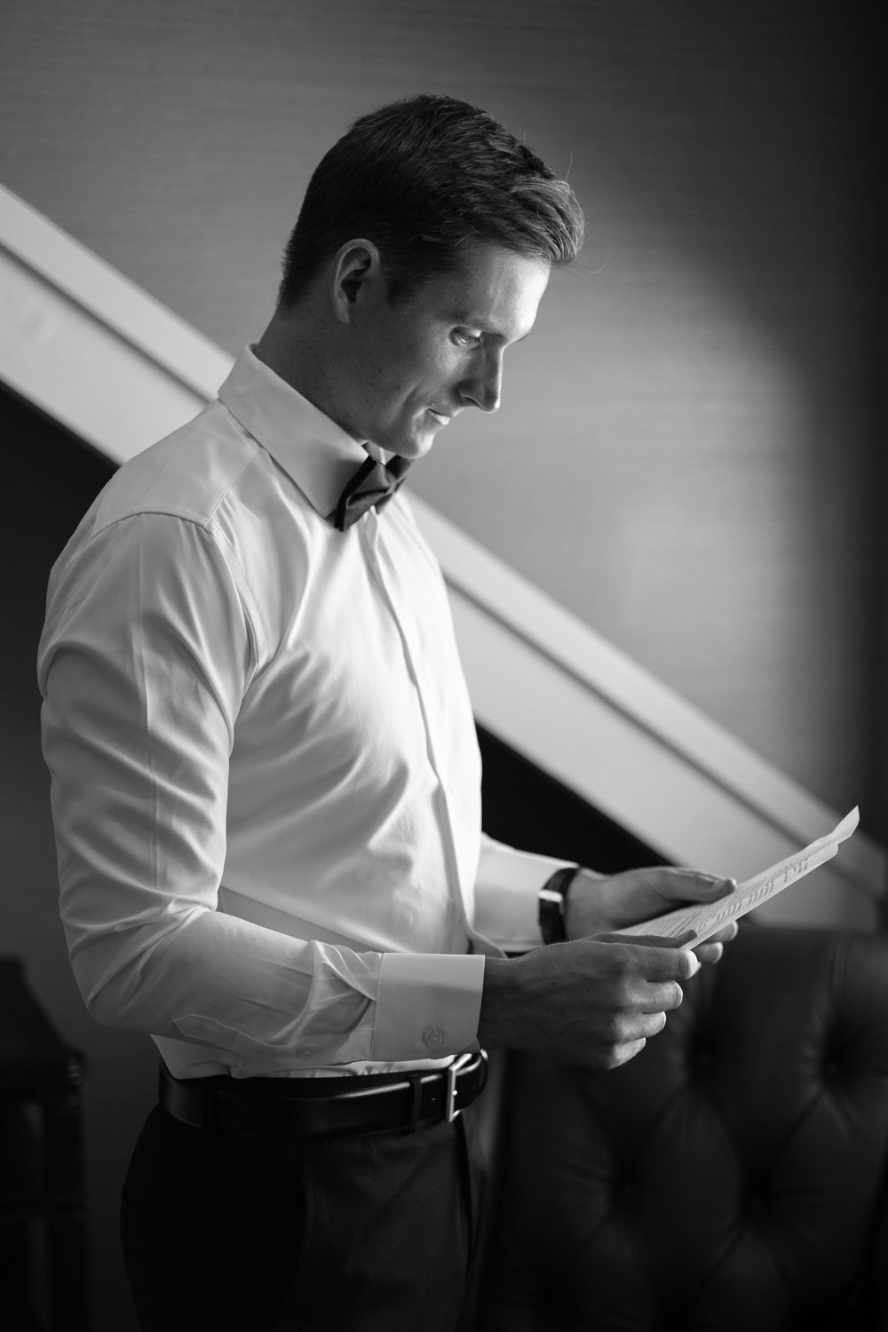 Black and white photo series of person in white shirt reading document in dramatic lighting.
