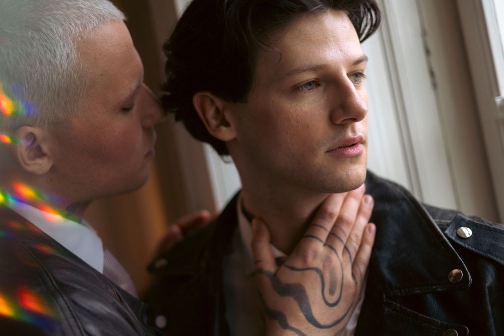 Two people in a dramatic scene by a window, with rainbow light reflections visible in the frame.