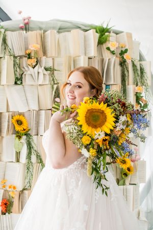 Wedding backdrop decorated with open books and bright sunflowers creating a whimsical literary theme.