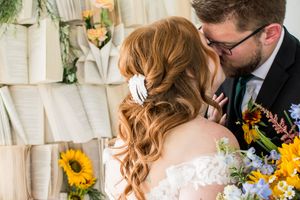 Wedding couple and party members posing with sunflower bouquets outdoors.