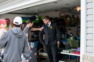 Wedding guest in suit jacket greets attendees in a casual garage setting.