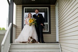 Wedding party gathered on a covered porch of a house with white siding.