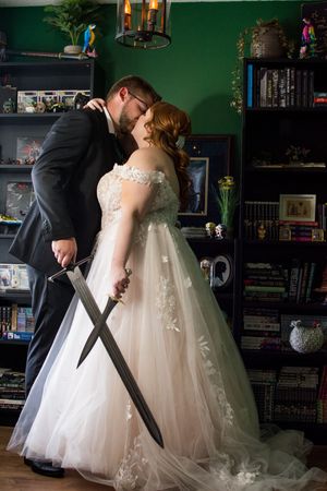 A wedding couple posing in a room with dark green walls and bookshelves.