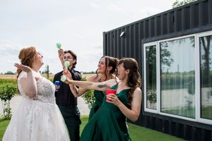 Wedding party celebrates with drinks and laughter at an outdoor reception.
