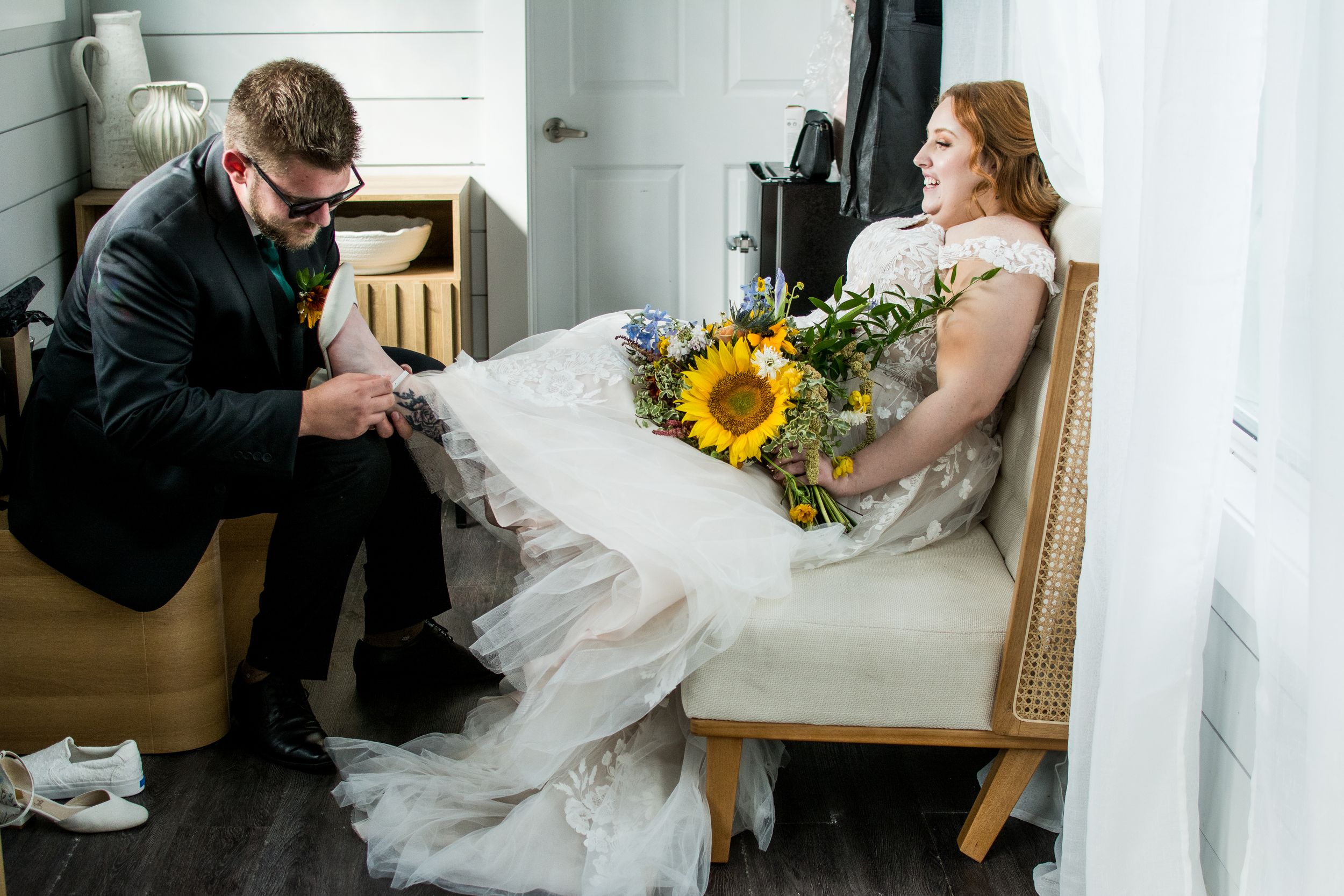 Wedding photographer captures intimate moments with bride and groom during an indoor photo session with sunflowers.