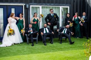 Wedding party seated in a row against modern building exterior.