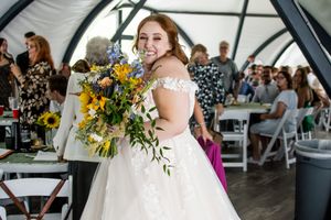 Wedding celebration under a white tent with sunflower decorations and guest seating.