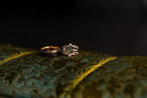 Wedding rings photographed in dramatic lighting on a textured surface.