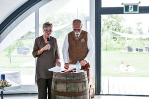 Wedding guests gather in a modern venue with large windows and natural lighting.