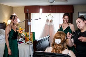Wedding preparation scene with women in emerald green dresses getting ready in a home setting.