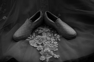 Black and white detail shot of wedding shoes and lace accessories.