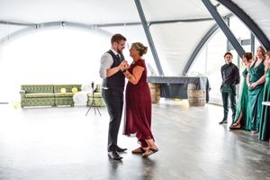 Dancers in burgundy and teal dresses perform a contemporary dance sequence in a bright studio space.