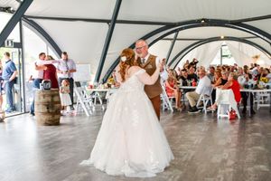 Dancers in flowing white dresses perform gracefully in a circular formation at an indoor venue.