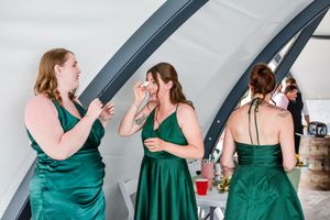 Bridesmaids in elegant emerald green dresses gathered during wedding celebration.