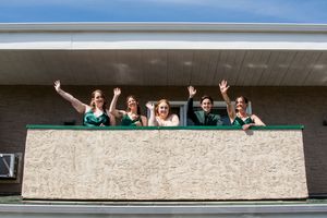 Wedding guests peek over balcony ledge for fun group photo.