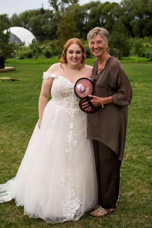 Heartwarming outdoor wedding moment captured on grassy field with white bridal gown.