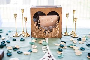 Wedding reception table setting with gold candlesticks and blue accents on light blue tablecloth.