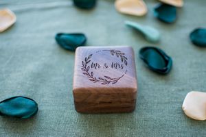 Wedding rings and decorative elements arranged on a teal colored surface.
