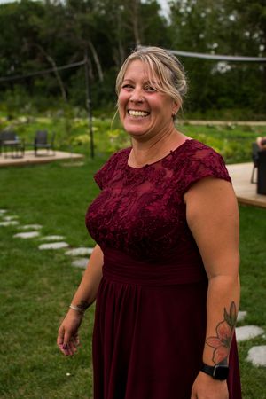 Guest in burgundy lace dress enjoying outdoor wedding festivities.