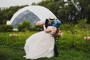 Creative wedding photography poses in a grassy field with geometric dome in background.