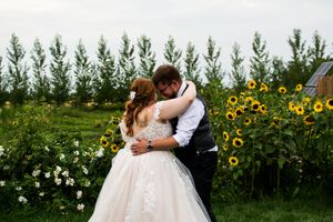 Romantic wedding portrait in a sunflower field with soft natural lighting.