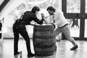 Wedding guests participate in a barrel rolling competition game at an indoor reception venue.