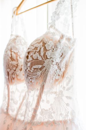 Delicate lace details of a wedding dress hanging in soft natural light.