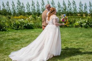 A romantic wedding moment captured in a garden setting with evergreen trees in the background.