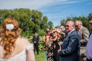 Outdoor wedding ceremony taking place on a beautiful sunny day with blue skies and green trees.
