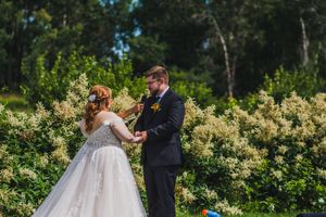 A romantic outdoor wedding moment captured in a lush green garden setting.
