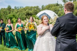 Wedding party celebrates on sunny day with bridesmaids in emerald dresses and groomsmen in dark suits.