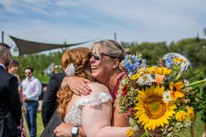 Outdoor wedding celebration features bright sunflower bouquets and emerald green attire.