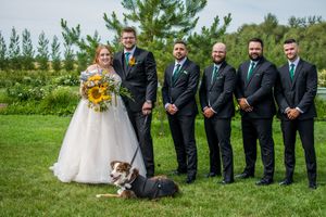 Wedding party standing outdoors with pine trees and green grass in the background.