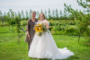 Outdoor wedding ceremony with sunflower bouquet against green natural landscape.