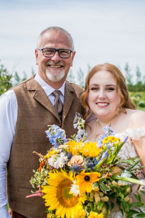 Vibrant sunflower bouquet with blue wildflowers creates stunning wedding floral arrangement.