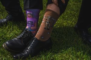 Close-up of formal shoes and boots on grass during outdoor wedding.