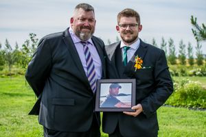 Wedding party members sharing laughs and holding a tablet device outdoors.