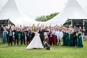 Large group wedding photo of guests and wedding party on sunny lawn.