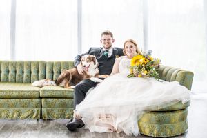 Wedding couple relaxing on vintage green couch in bright indoor setting.