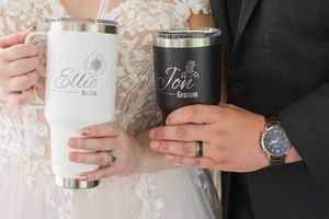 Hands holding customized stainless steel tumblers with names written on them.