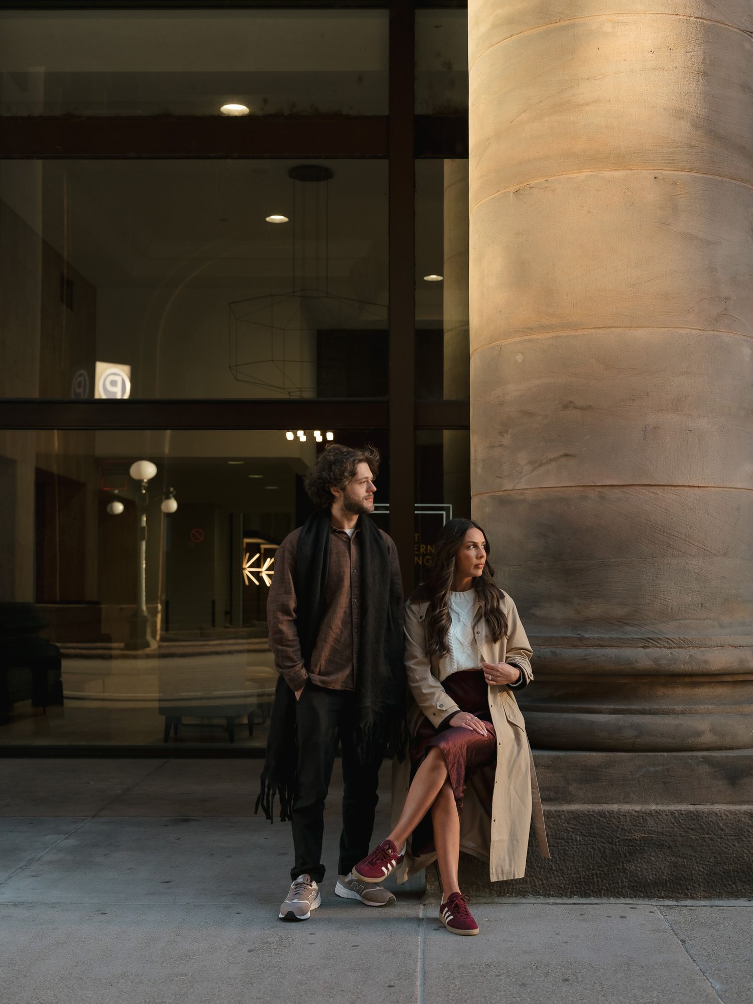 Two people engage in a playful dance sequence under architectural columns in a dimly lit space.