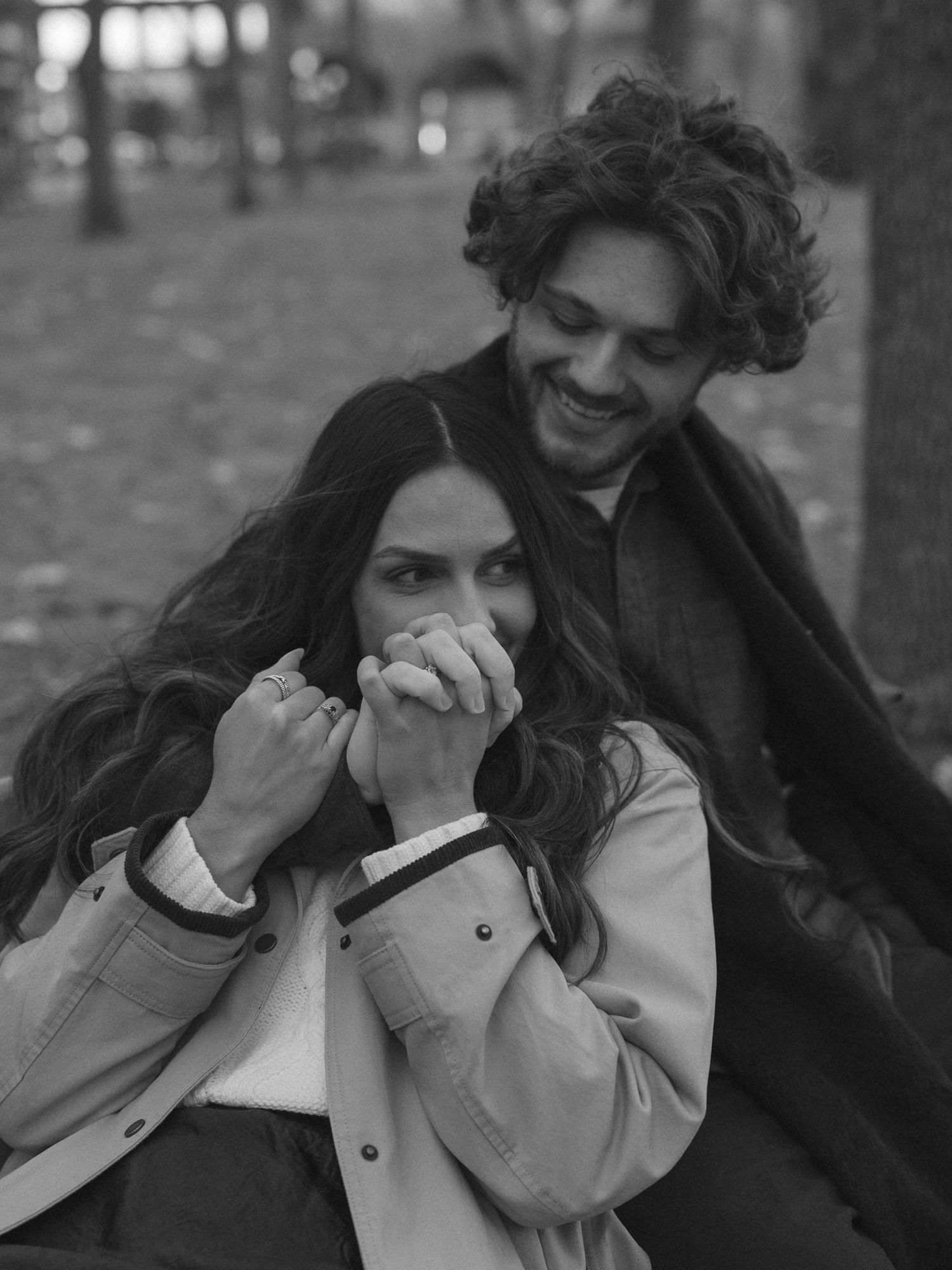 A couple shares an intimate black and white moment together in a park setting.