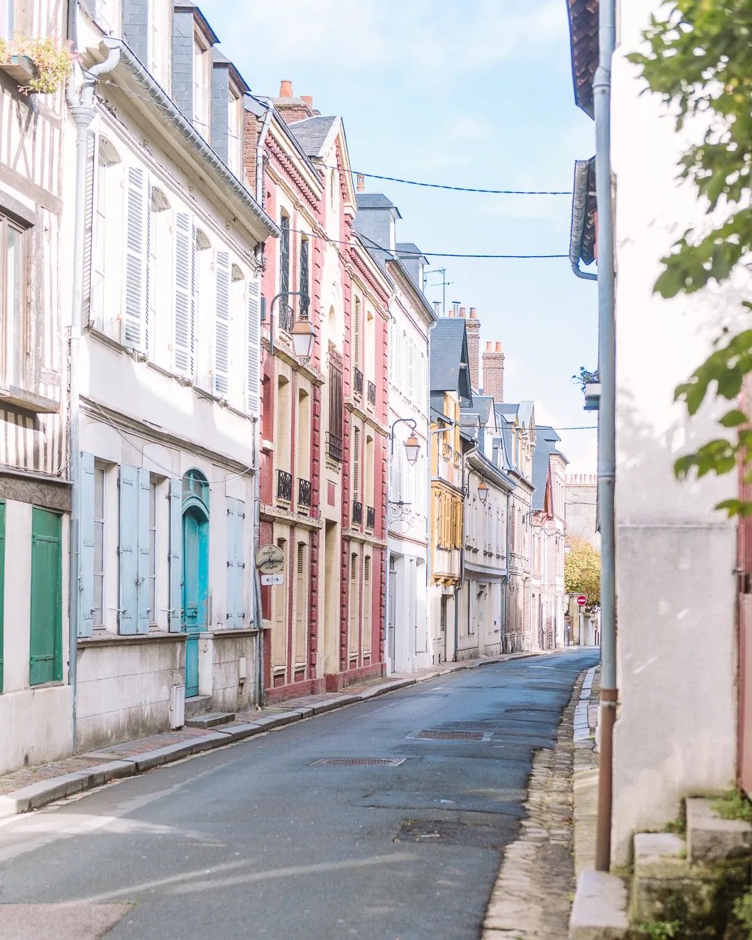 Quiet pastel-coloured street lined with traditional French houses in soft morning light.
