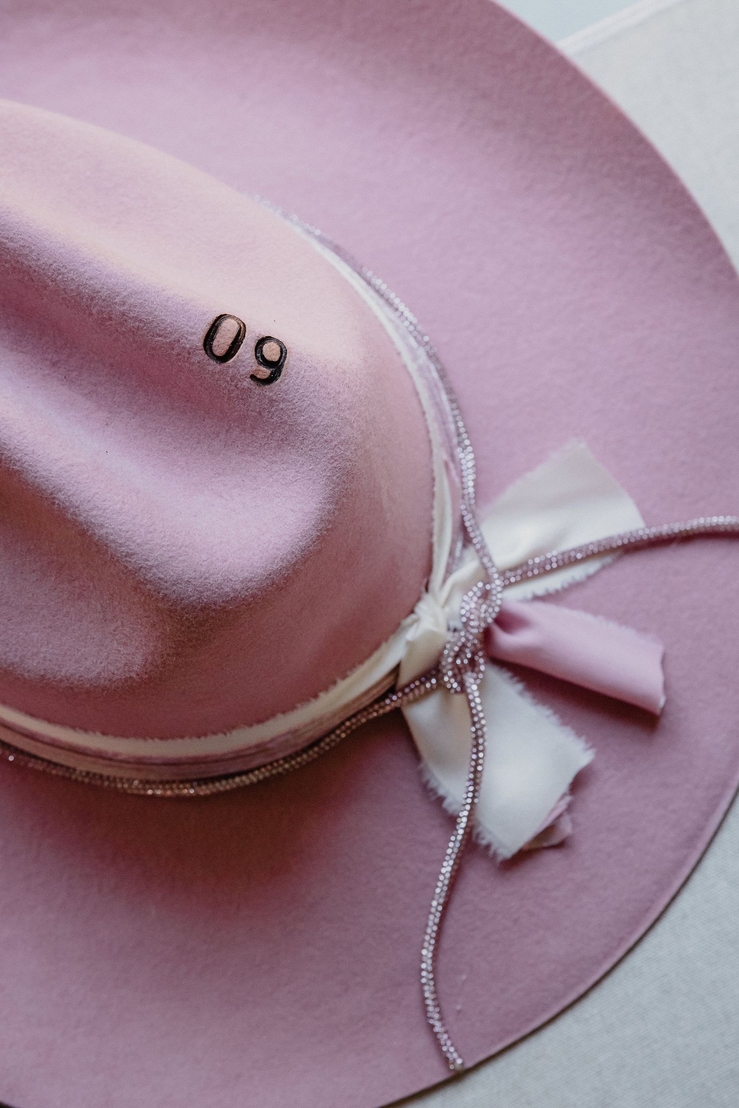 Pink felt hat with white ribbon and sparkly silver trim detail shown from multiple angles.