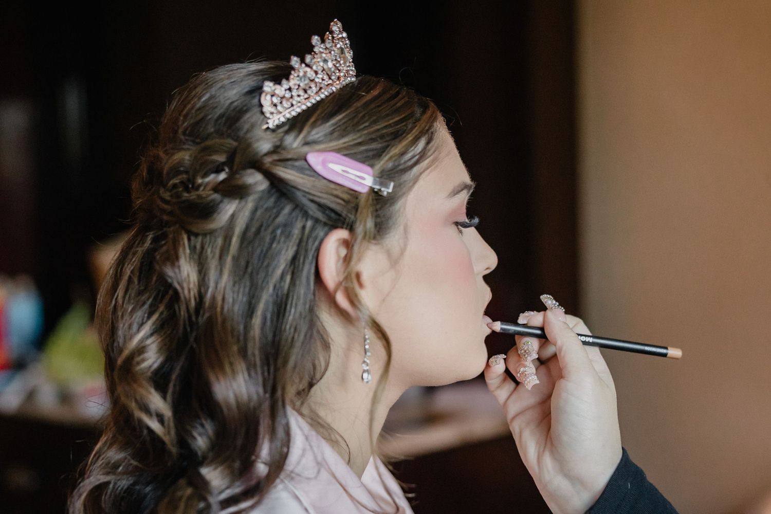 Close-up shot of makeup application with a sparkling tiara and elegant updo hairstyle.