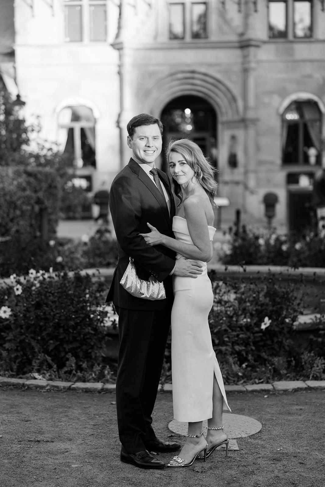 A romantic black and white photo sequence shows a couple dancing and embracing in a garden setting near a historic building.
