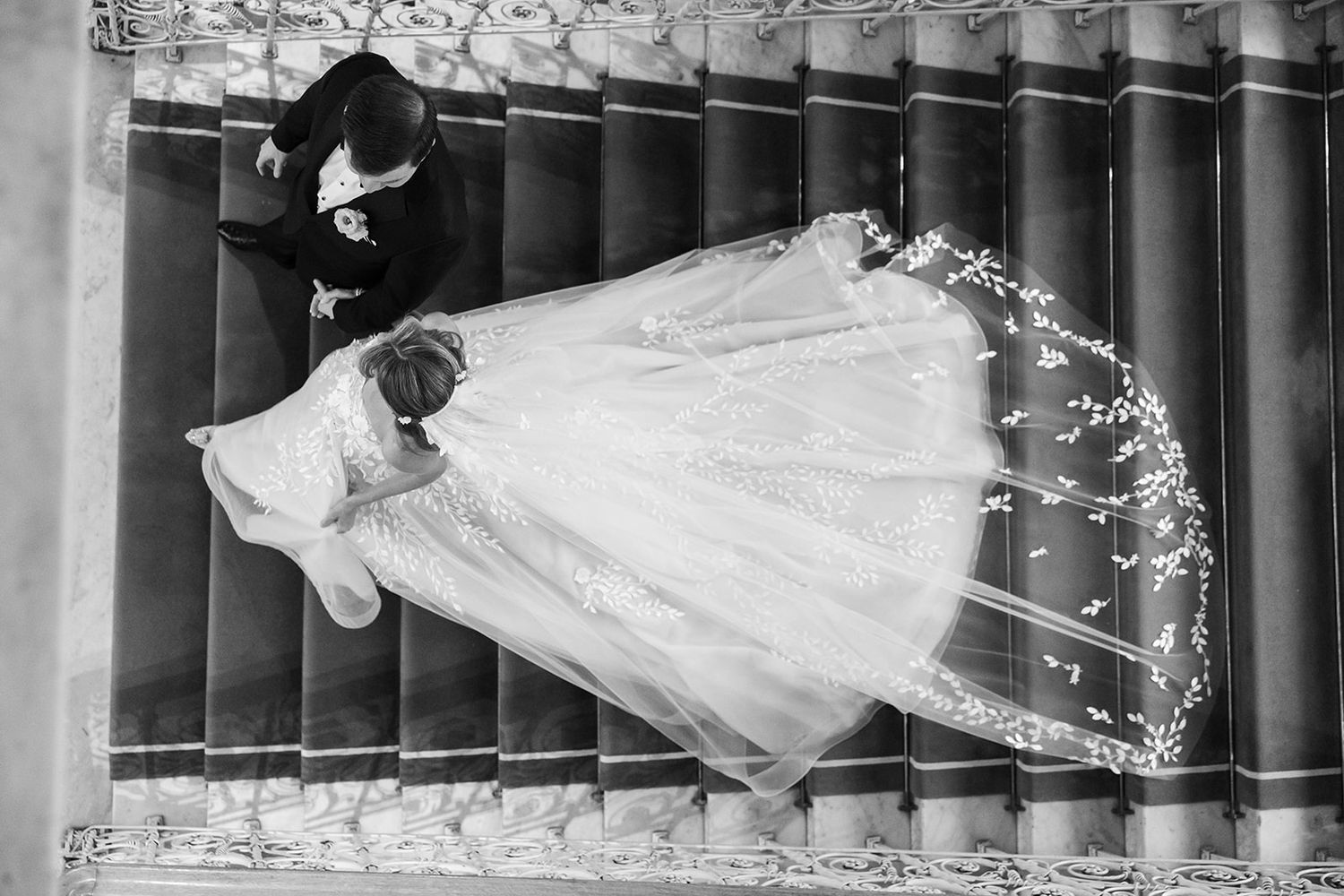 A black and white vintage photograph shows a person in a flowing white dress floating through a dark library.