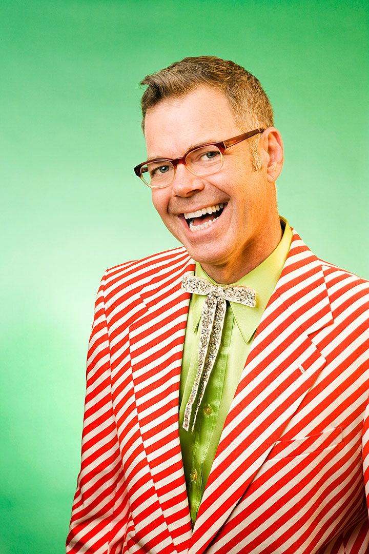 A person in a red and white striped shirt makes silly faces while holding a cucumber against their face.