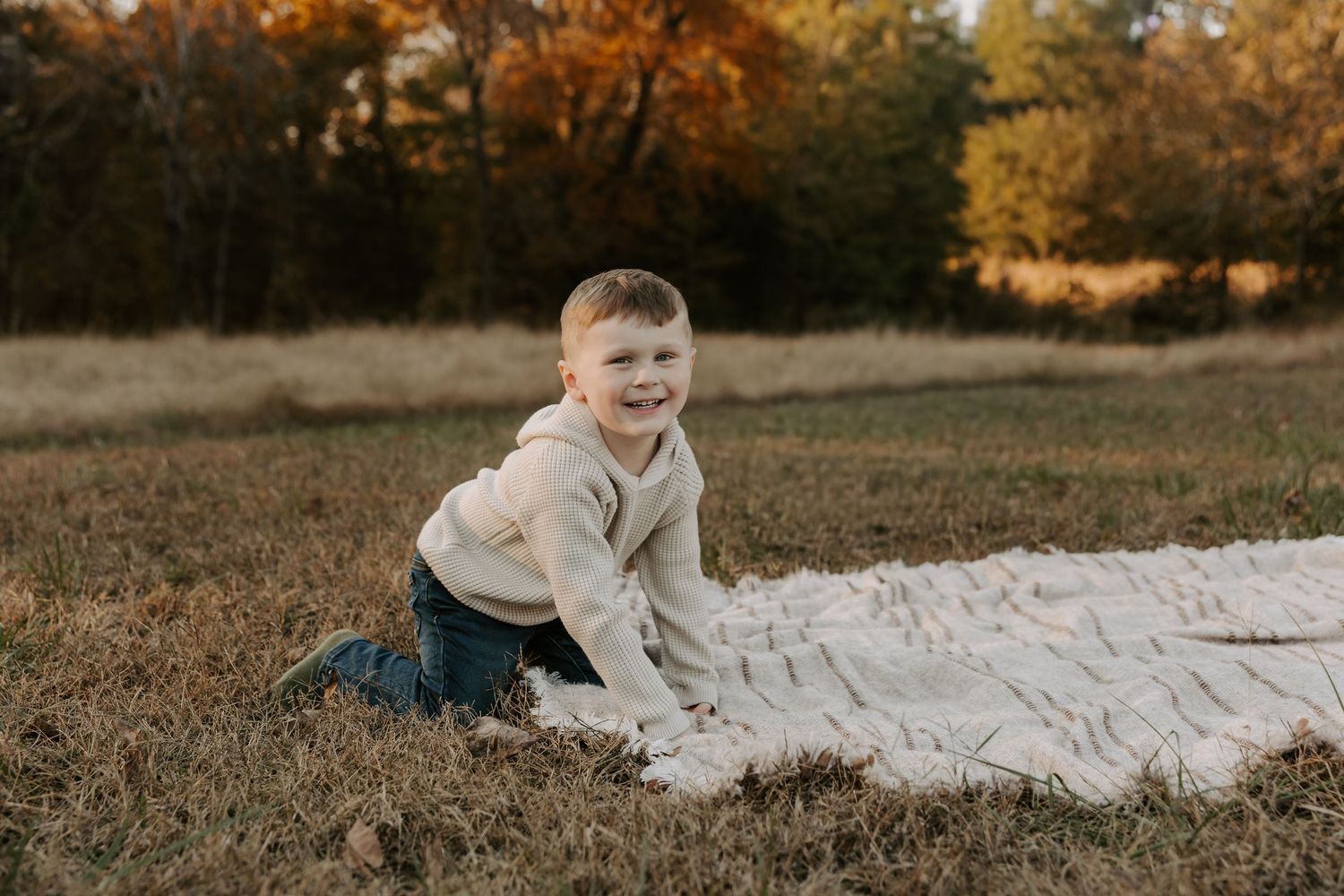 Children playing and rolling on white blanket during fall family photoshoot.